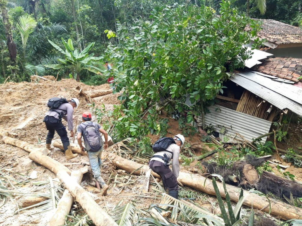 Anggota Brimob Kompi 4 Batalyon B Pelopor Cipanas membersihkan jalan tertutup longsor di Kampung Munjul, Desa Karangnunggal, Kecamatan Cibeber, Kabupaten Cianjur, Senin (23/03/2020).