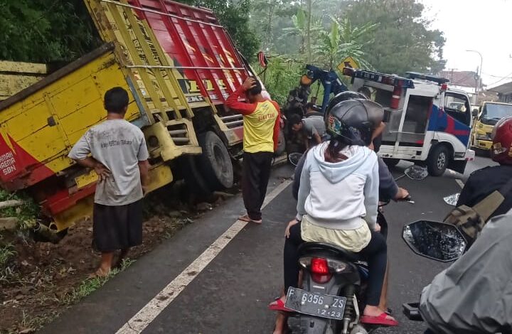 TERPEROSOK: Akibat hilang kendali, sebuah mobil roda enam jenis Mitsubishi Colt Diesel terperosok ke parit di Jalan Raya Cugenang, pada Selasa (16/2/2021). (Foto: Rendi Irawan/cianjurupdate.com)