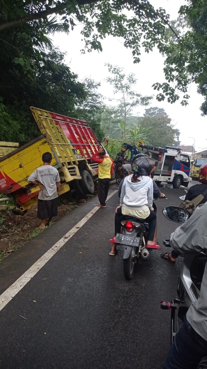 TERPEROSOK: Akibat hilang kendali, sebuah mobil roda enam jenis Mitsubishi Colt Diesel terperosok ke parit di Jalan Raya Cugenang, pada Selasa (16/2/2021). (Foto: Rendi Irawan/cianjurupdate.com)