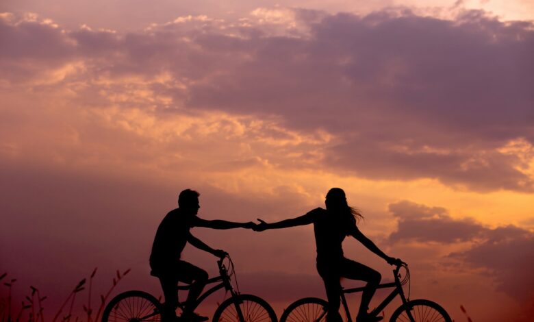 woman on bike reaching for man's hand behind her also on bike