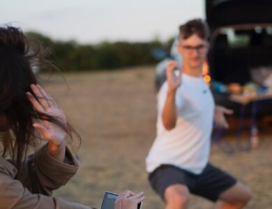 woman in white t-shirt and brown jacket holding smartphone