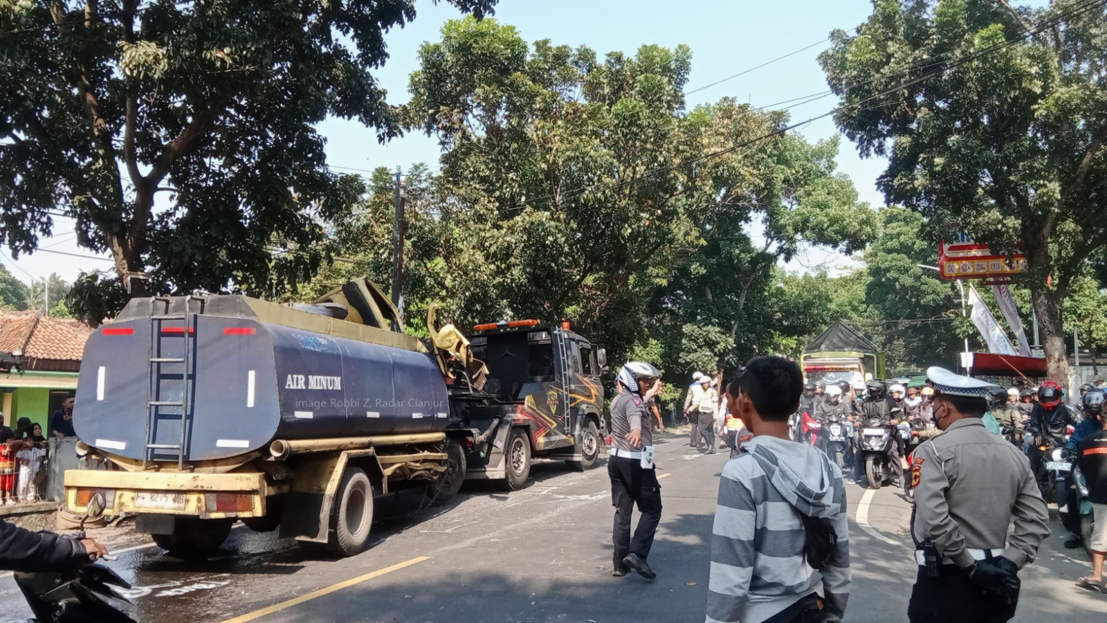 Truk tangki bermuatan air terperosok usai terlibat tabrakan dengan motor di jalan raya Bandung Kecamatan Karangtengah, Cianjur.