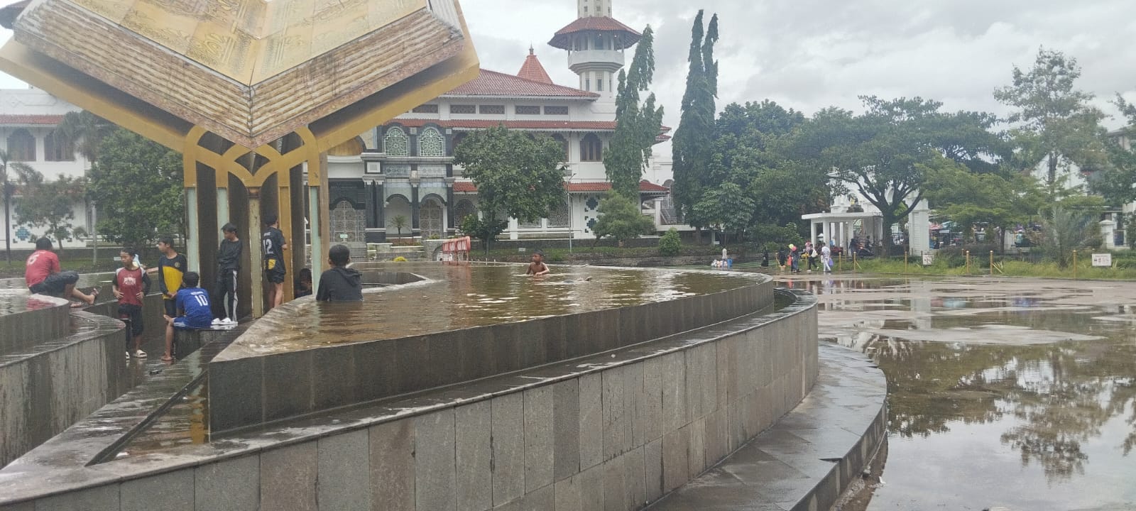 Anak-anak jadikan kolam Alun-alun Cianjur tempat berenang di tengah hujan deras. Pemkab Cianjur prihatin dan akan meningkatkan pengamanan.