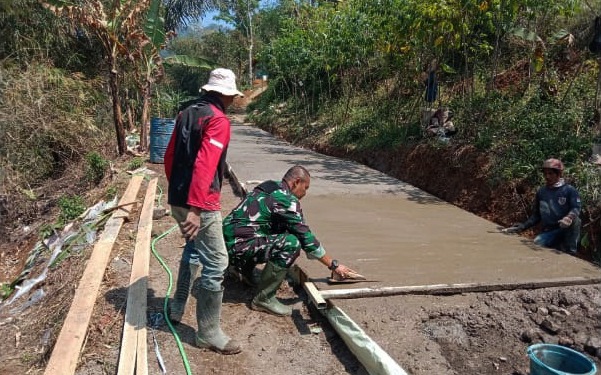 Babinsa Desa Wangunjaya, Serda Tato, bersama warga melaksanakan pengecoran jalan untuk meningkatkan infrastruktur desa.