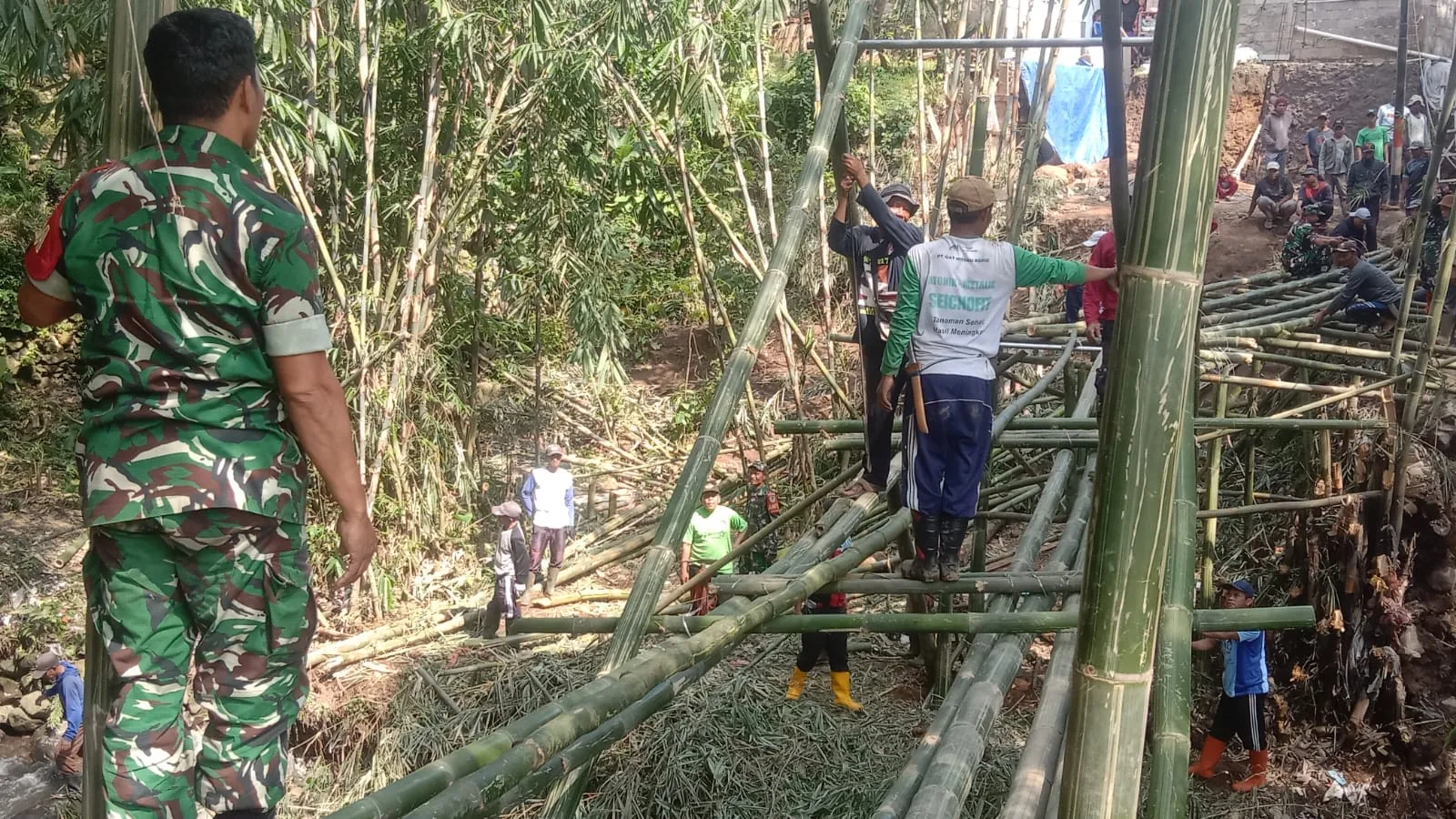 Koramil Cipanas membangun jembatan darurat bambu di Desa Ciwalen pasca jembatan putus akibat banjir.