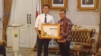 Bupati Cianjur, dr. M Wahyu Ferdian (kiri), saat menerima piagam penghargaan Universal Health Coverage (UHC) Prioritas dari Direktur Utama BPJS, David Bangun, Jumat (26/9/2025). Pencapaian ini menjadi penanda bahwa seluruh warga Cianjur kini dapat berobat gratis hanya dengan KTP.
