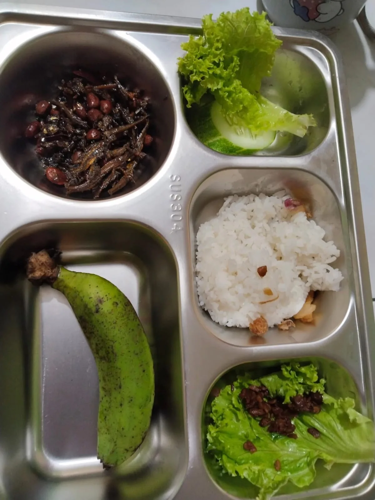 Tampilan sajian Makan Bergizi Gratis (MBG) berisi nasi, olahan ikan teri kacang, dan pisang yang disajikan untuk siswa TK di Kecamatan Cikalongkulon, Cianjur. Menu ini sempat viral dan menuai beragam reaksi publik terkait kesesuaian lauk bagi anak usia dini. (foto: Istimewa)
