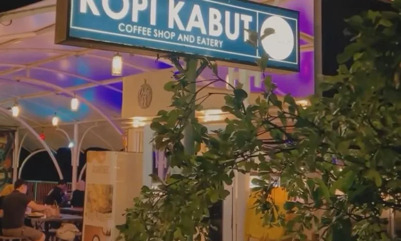 SUASANA malam di Kopi Kabut Coffee Shop and Eatery. Papan nama kafe yang menyala terang menyambut pengunjung yang tengah menikmati waktu bersantai.