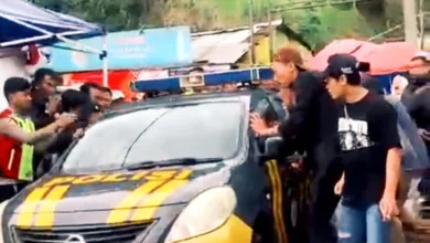 Mobil patroli Polsek Pacet saat mengevakuasi juru parkir berinisial E (30) dari kepungan warga di Rest Area Segar Alam, Puncak, Cianjur, Sabtu (27/12/2025).