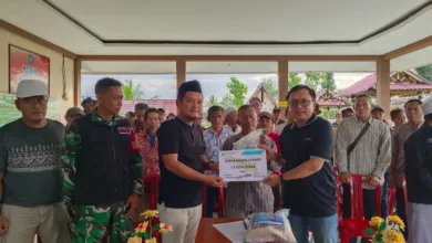Kepala Desa Sukamanah, Indra Surya Pradana (kiri), menyerahkan secara simbolis donasi 1,5 ton beras kepada Pimpinan Cianjur Update, Indra Arfiandi (kanan), disaksikan oleh Babinsa dan unsur RT/RW di Aula Agro Edu Wisata Tani Arta Sukamanah, Sabtu (13/12/2025).