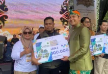 Bupati Cianjur (kanan) didampingi Kabid Pemasaran Pariwisata Disbudpar Cianjur, Tita Rosilawati (kiri), menyerahkan penghargaan secara simbolis kepada Yayan Sopyan (tengah) sebagai Juara 1 Sayembara City Branding Pariwisata Kabupaten Cianjur dalam acara Karnaval Lengkah Ka Jaman Anyar, Jumat (20/12/2025).